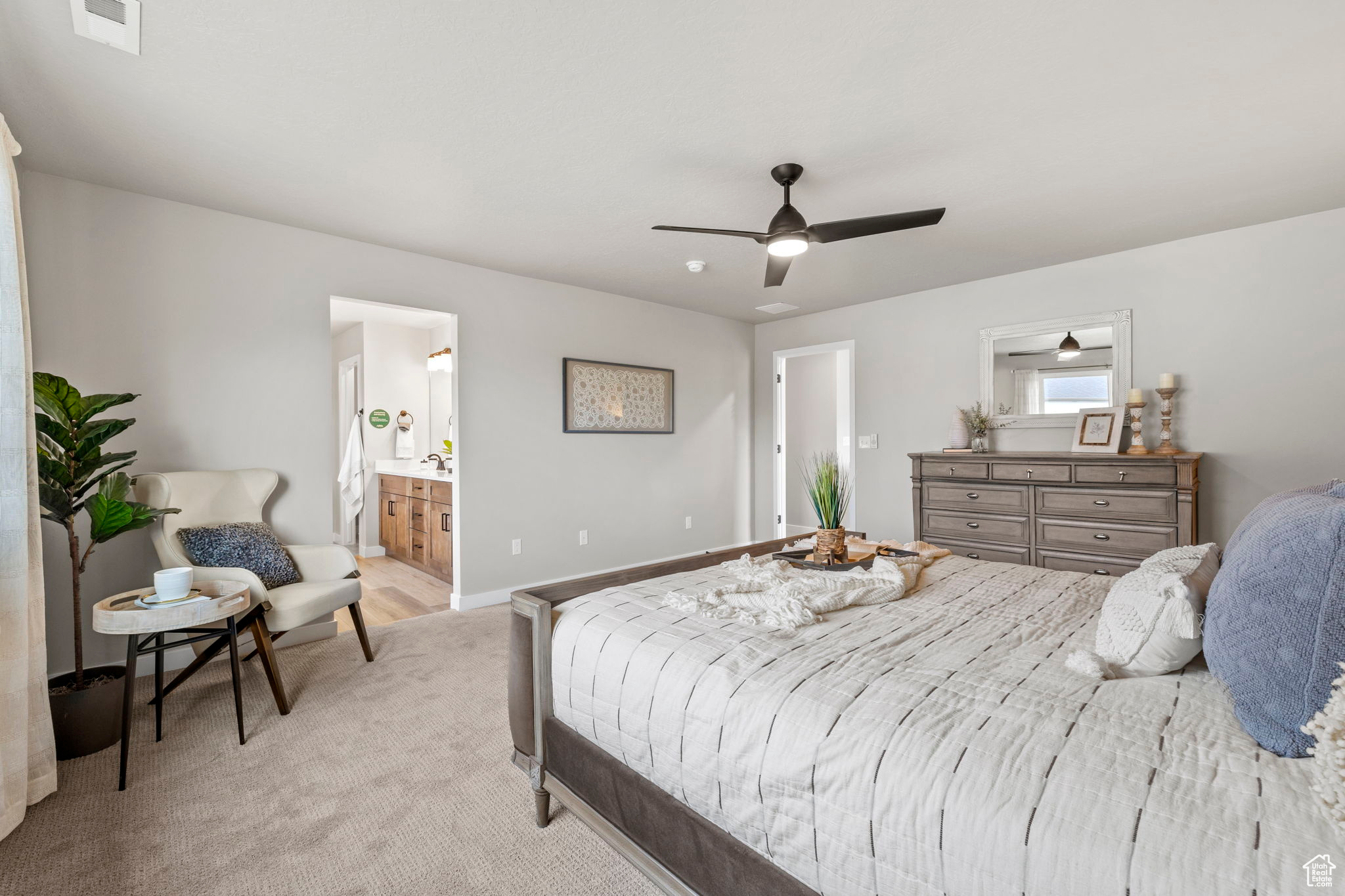 Carpeted bedroom with ensuite bathroom and ceiling fan