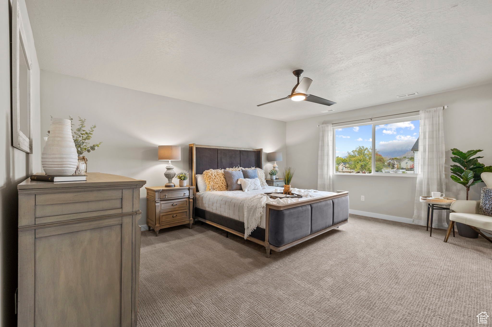 Carpeted bedroom with a textured ceiling and ceiling fan