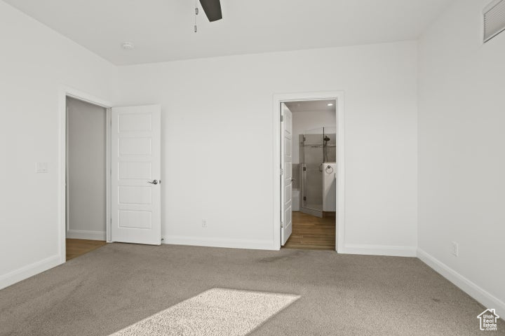 Unfurnished bedroom with ceiling fan, carpet flooring, and ensuite bathroom