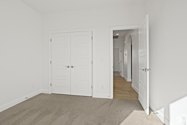 Unfurnished bedroom with a closet and light colored carpet