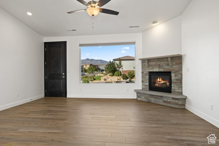 Unfurnished living room with a mountain view, hardwood / wood-style flooring, a fireplace, and ceiling fan