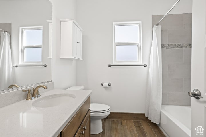 Full bathroom with vanity, toilet, wood-type flooring, and a wealth of natural light