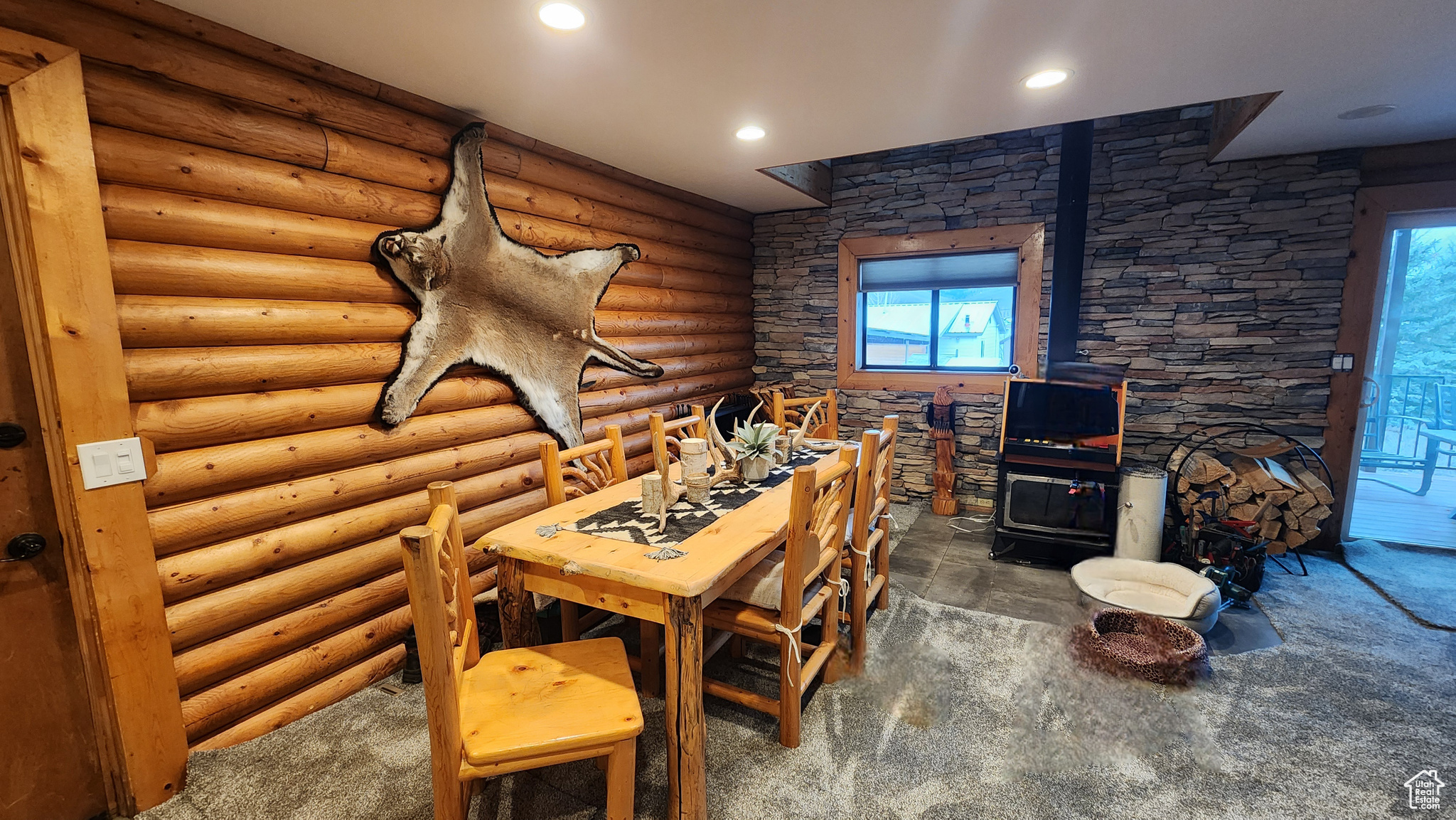 Dining space featuring log walls, dark carpet, and a wood stove