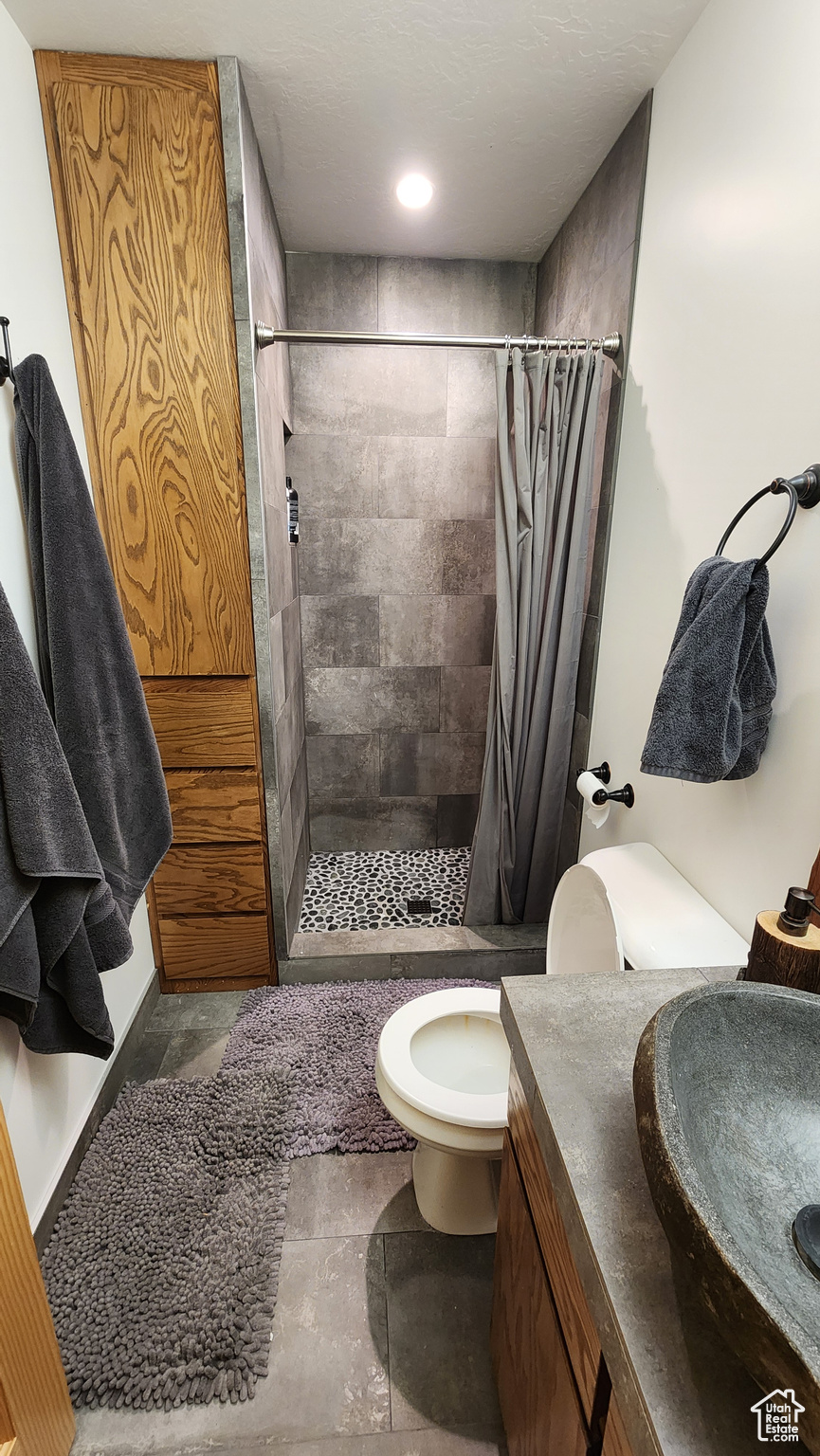 Bathroom featuring vanity, a shower with curtain, toilet, and tile patterned floors