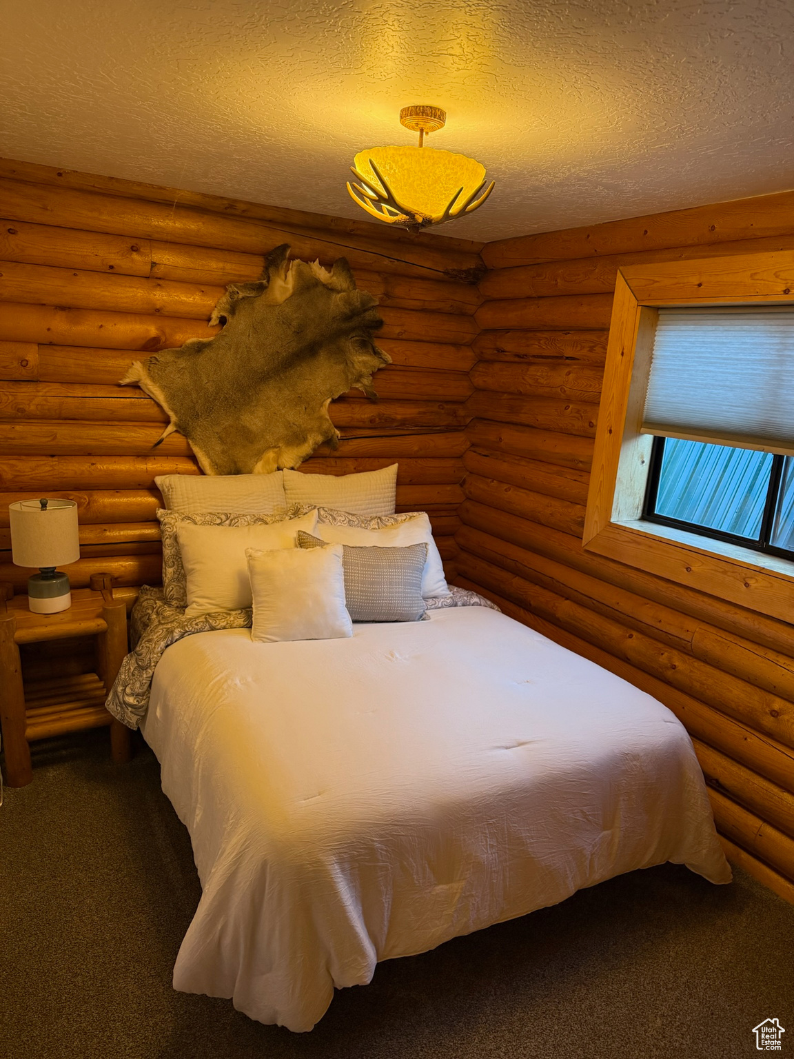 Bedroom featuring log walls, a textured ceiling, and carpet flooring