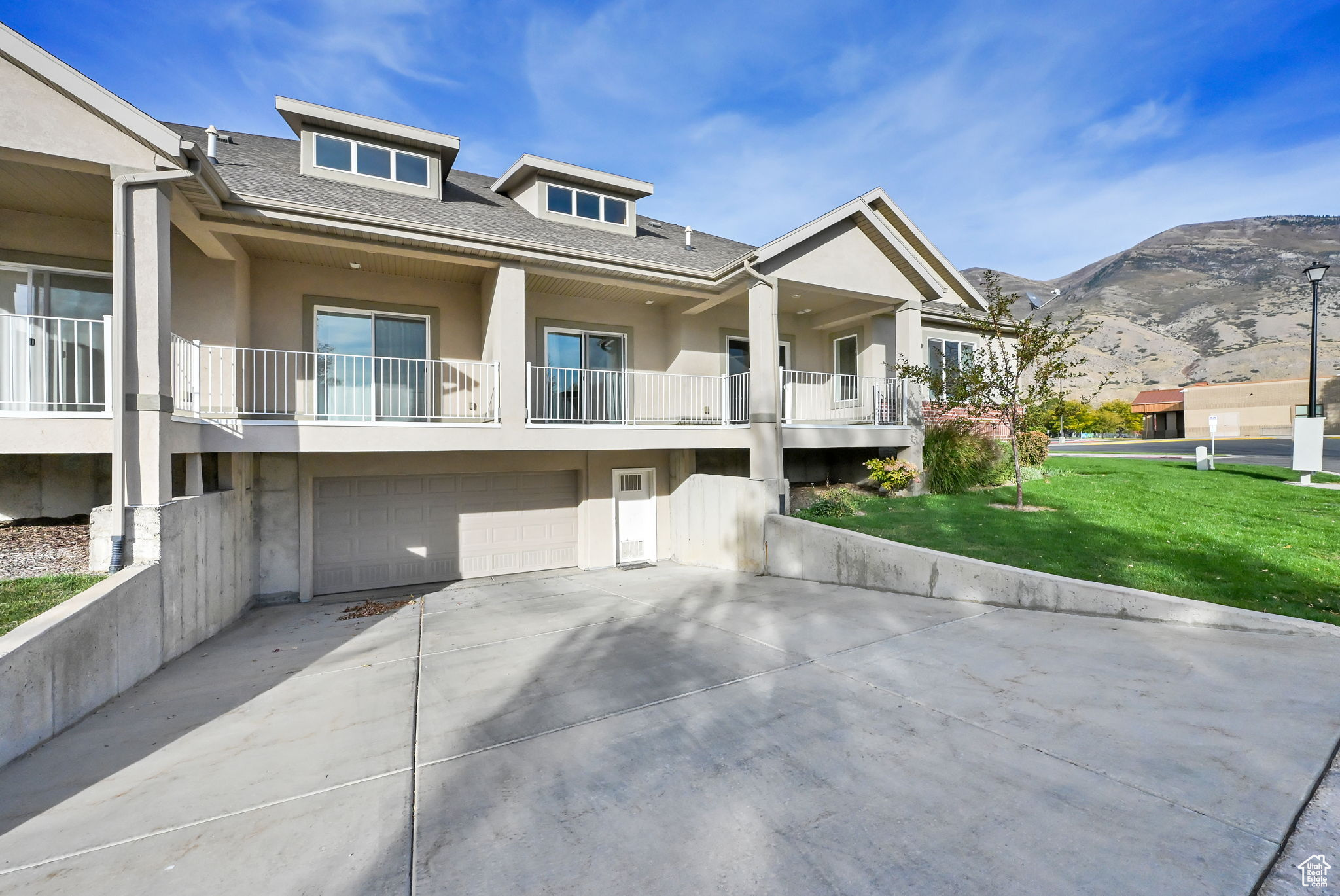 View of front of property with a balcony, a front yard, a garage, and a mountain view