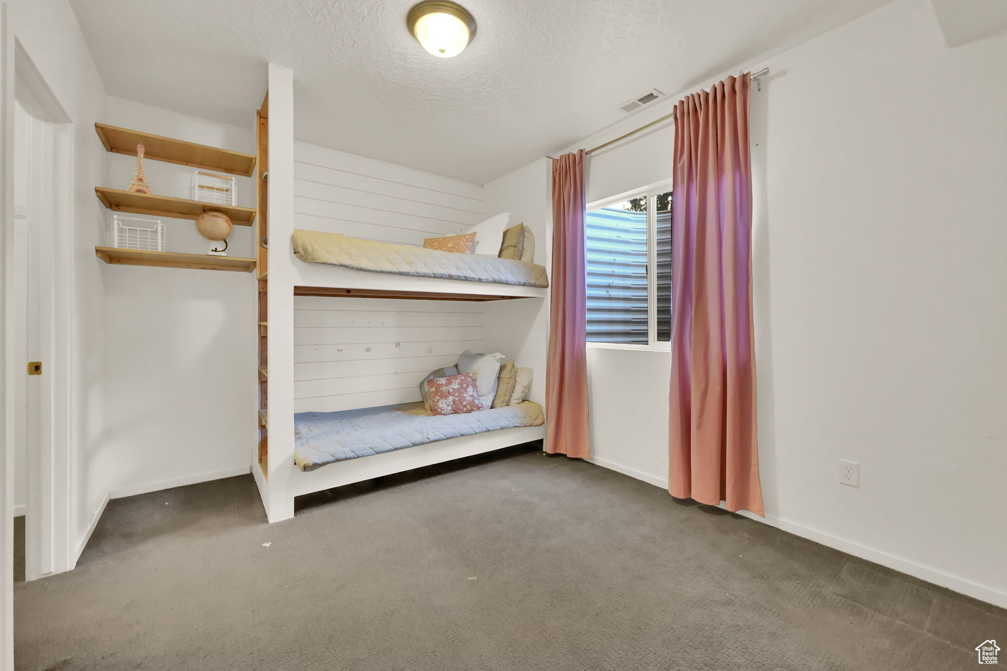 Unfurnished bedroom featuring a textured ceiling and dark carpet