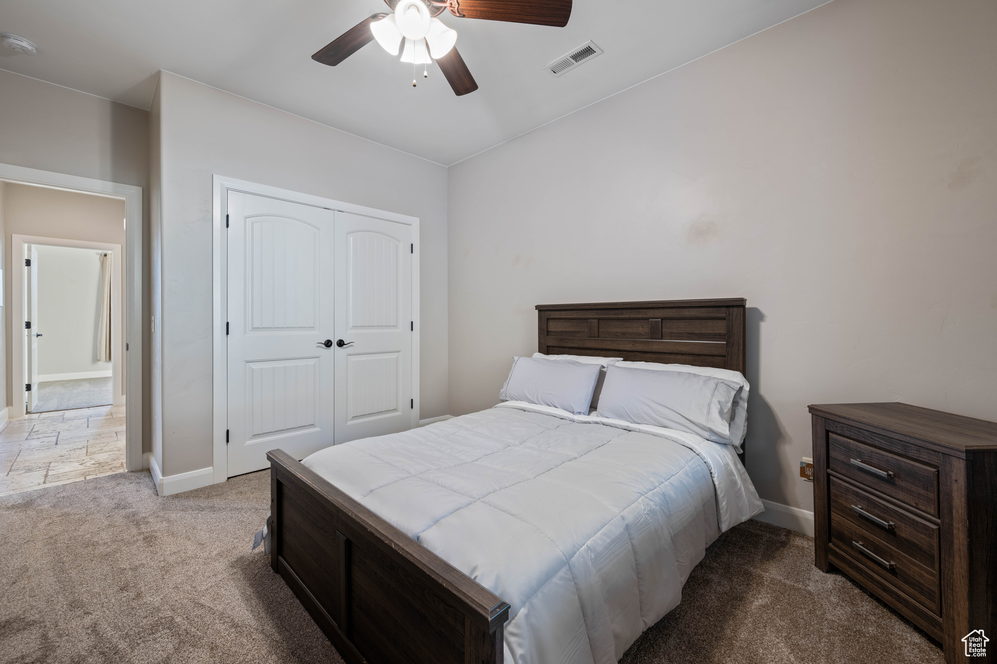 Bedroom with a closet, light colored carpet, and ceiling fan