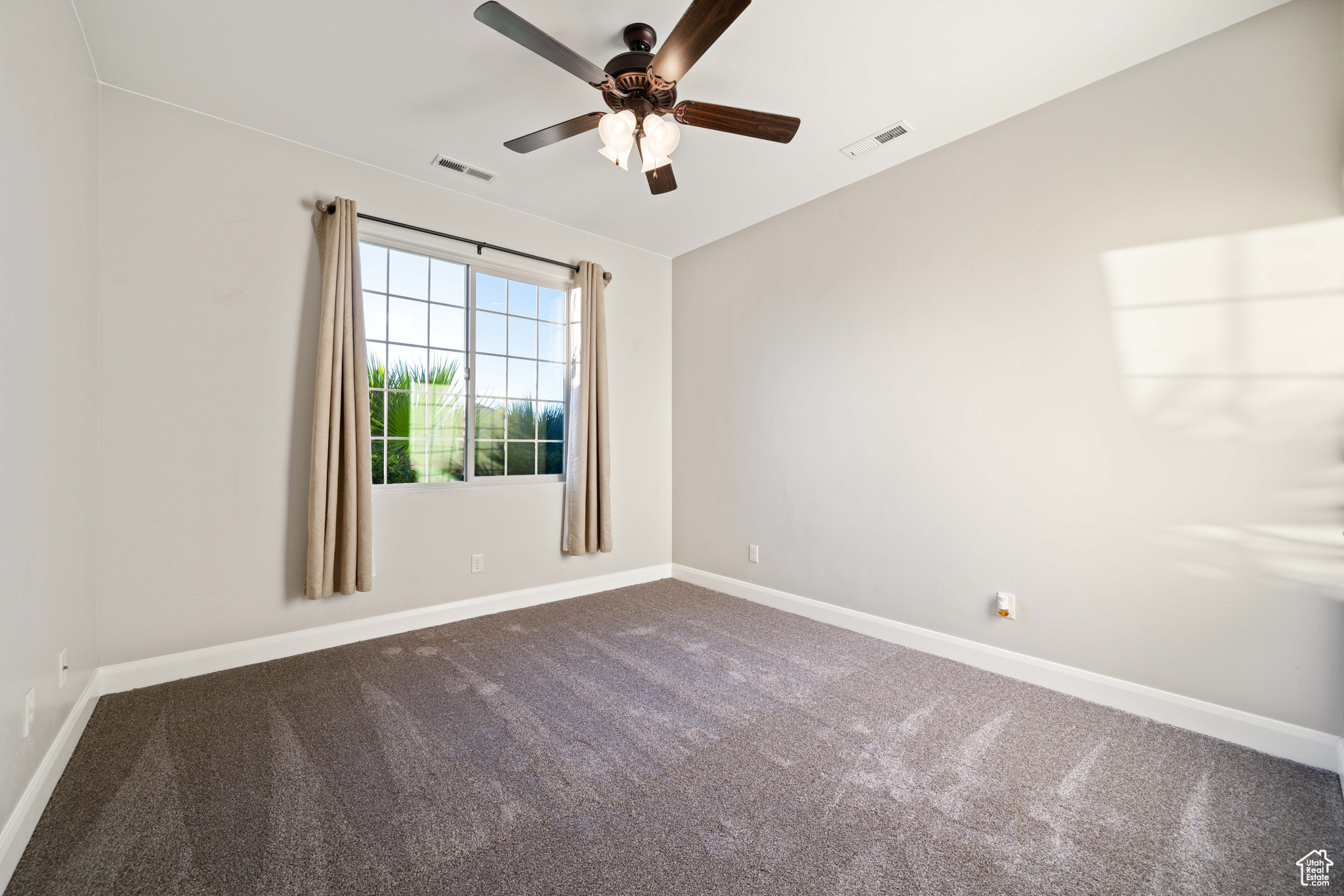 Carpeted spare room with ceiling fan