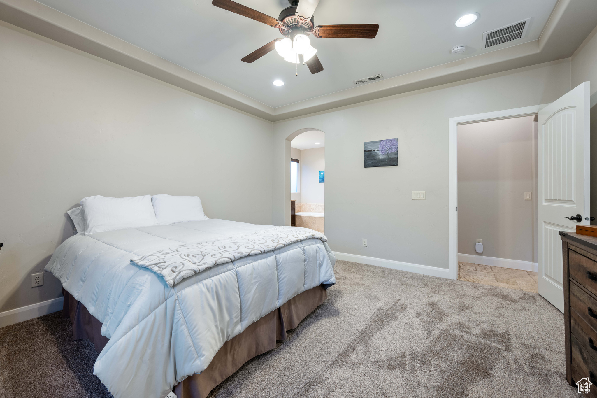 Carpeted bedroom featuring connected bathroom and ceiling fan