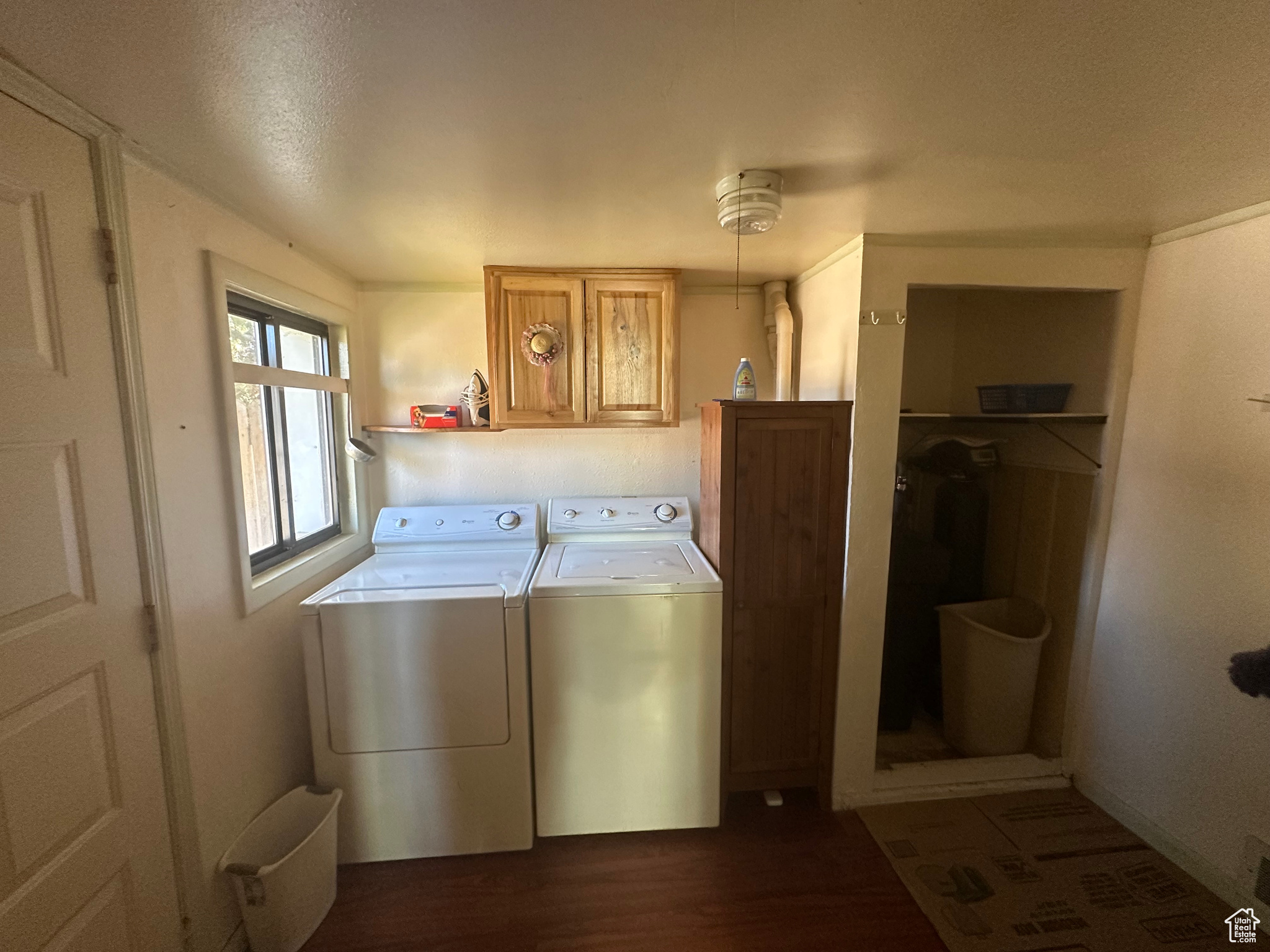 Clothes washing area featuring a textured ceiling, washing machine and dryer, cabinets, and dark hardwood / wood-style flooring