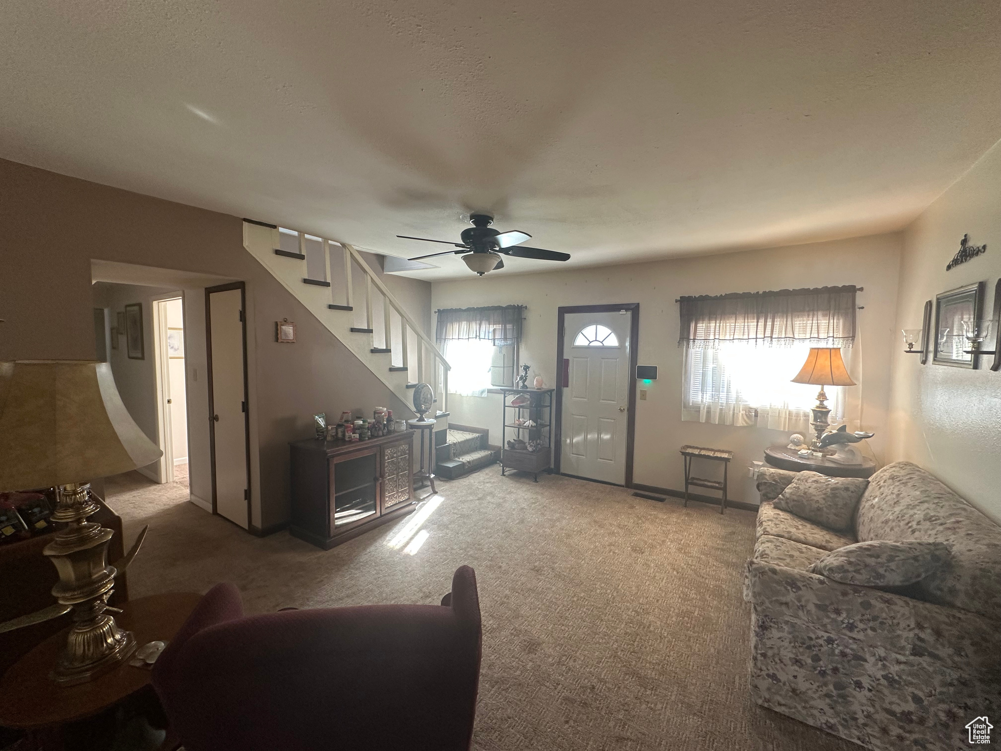 Living room with carpet floors, a healthy amount of sunlight, and ceiling fan