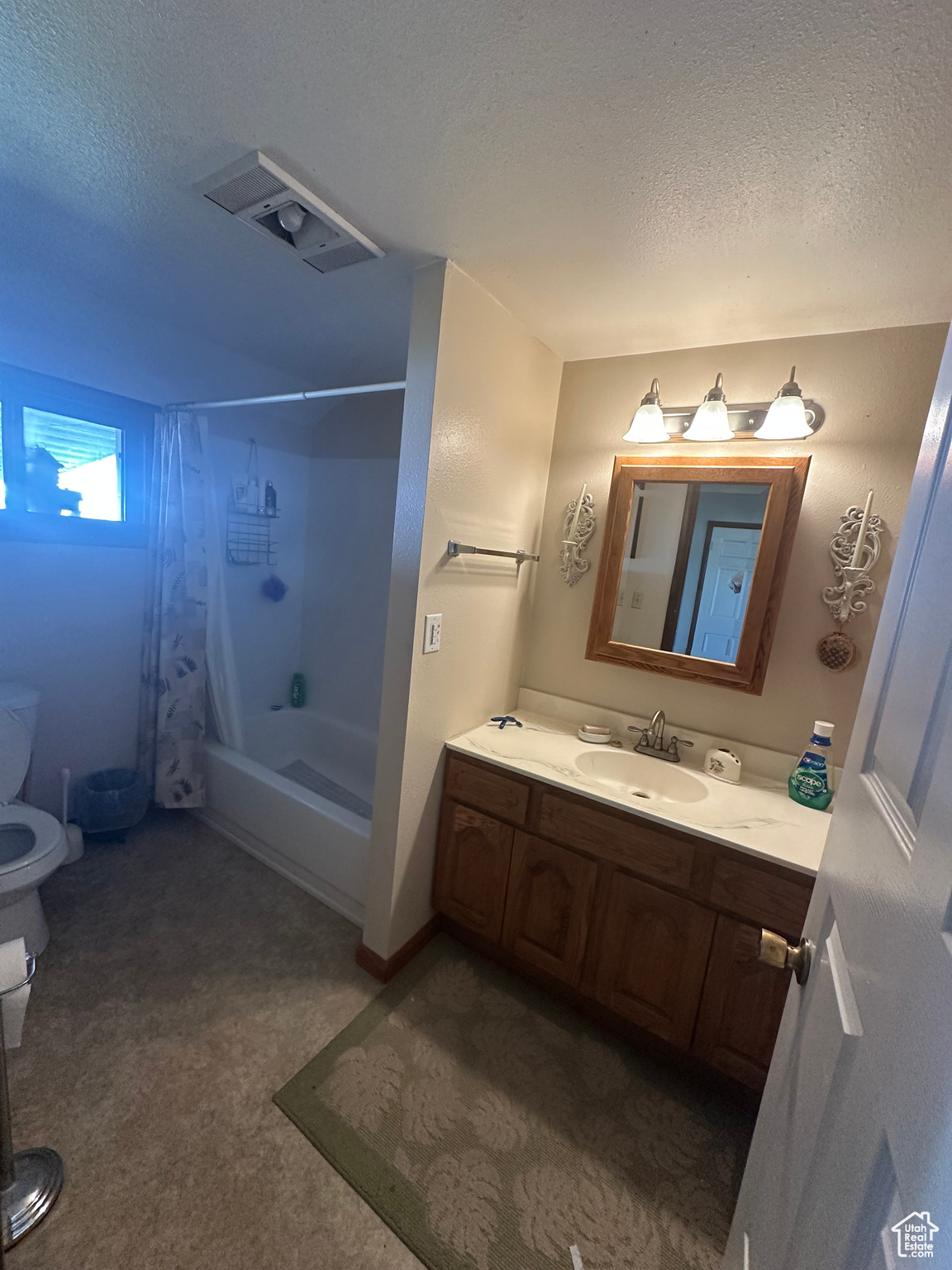 Full bathroom featuring vanity, shower / tub combo with curtain, a textured ceiling, and toilet