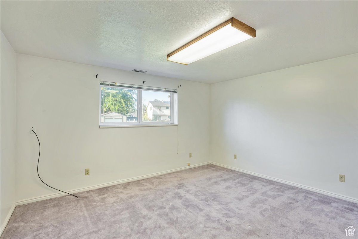 Unfurnished room featuring a textured ceiling and light colored carpet