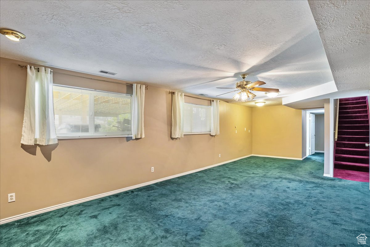 Empty room with a textured ceiling, carpet, and ceiling fan