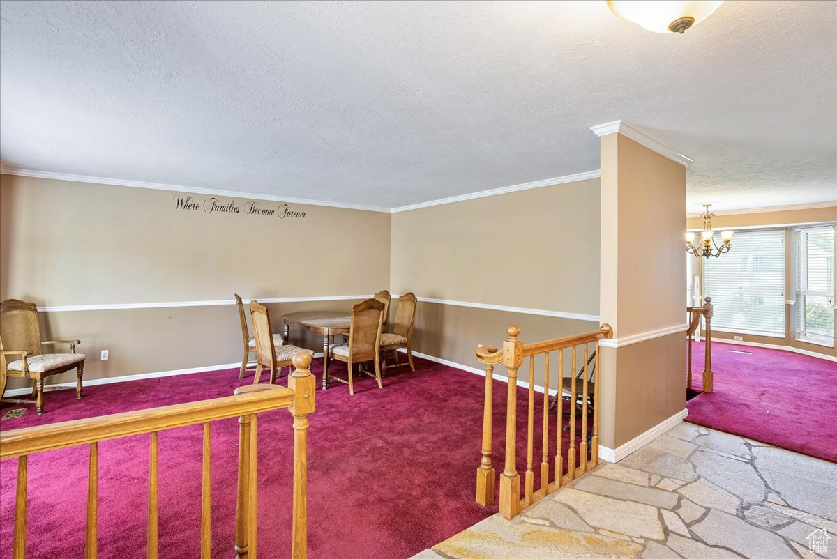 Interior space with crown molding, a notable chandelier, and a textured ceiling