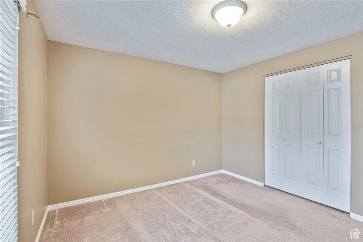 Unfurnished bedroom with a closet, carpet flooring, and a textured ceiling