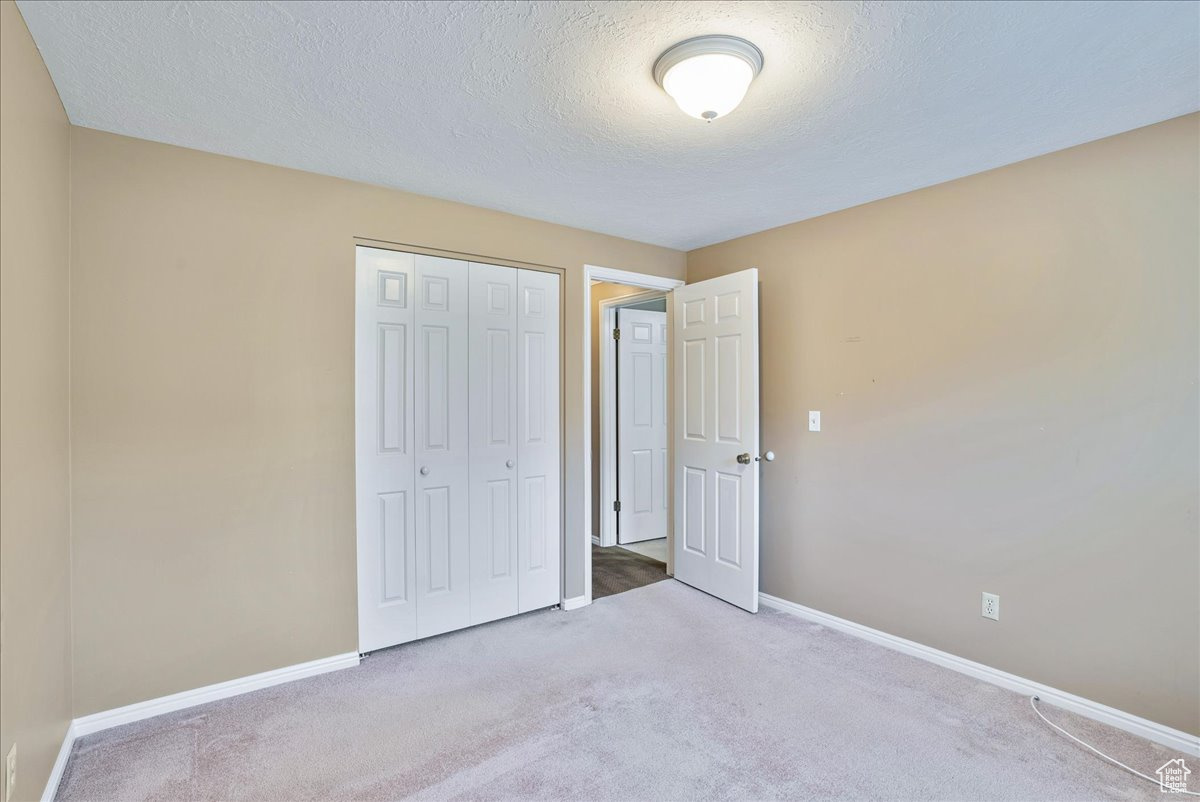 Unfurnished bedroom with a closet, carpet floors, and a textured ceiling