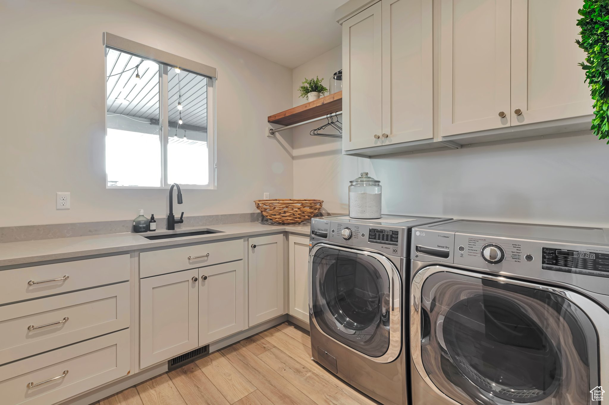 Washroom with light hardwood / wood-style floors, independent washer and dryer, sink, and cabinets