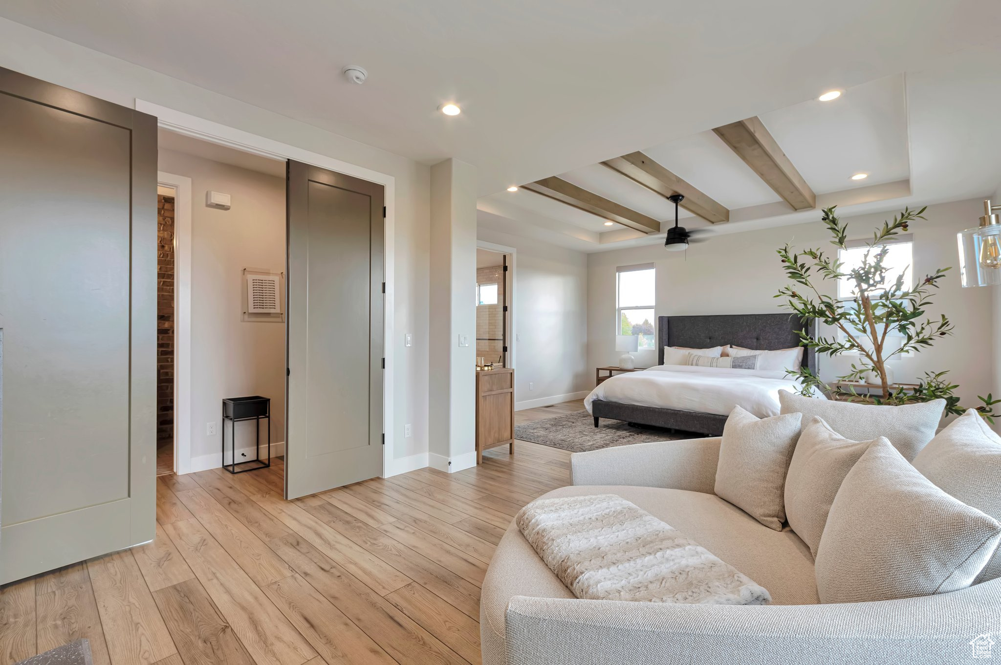 Bedroom with beam ceiling, ensuite bath, light wood-type flooring, and ceiling fan