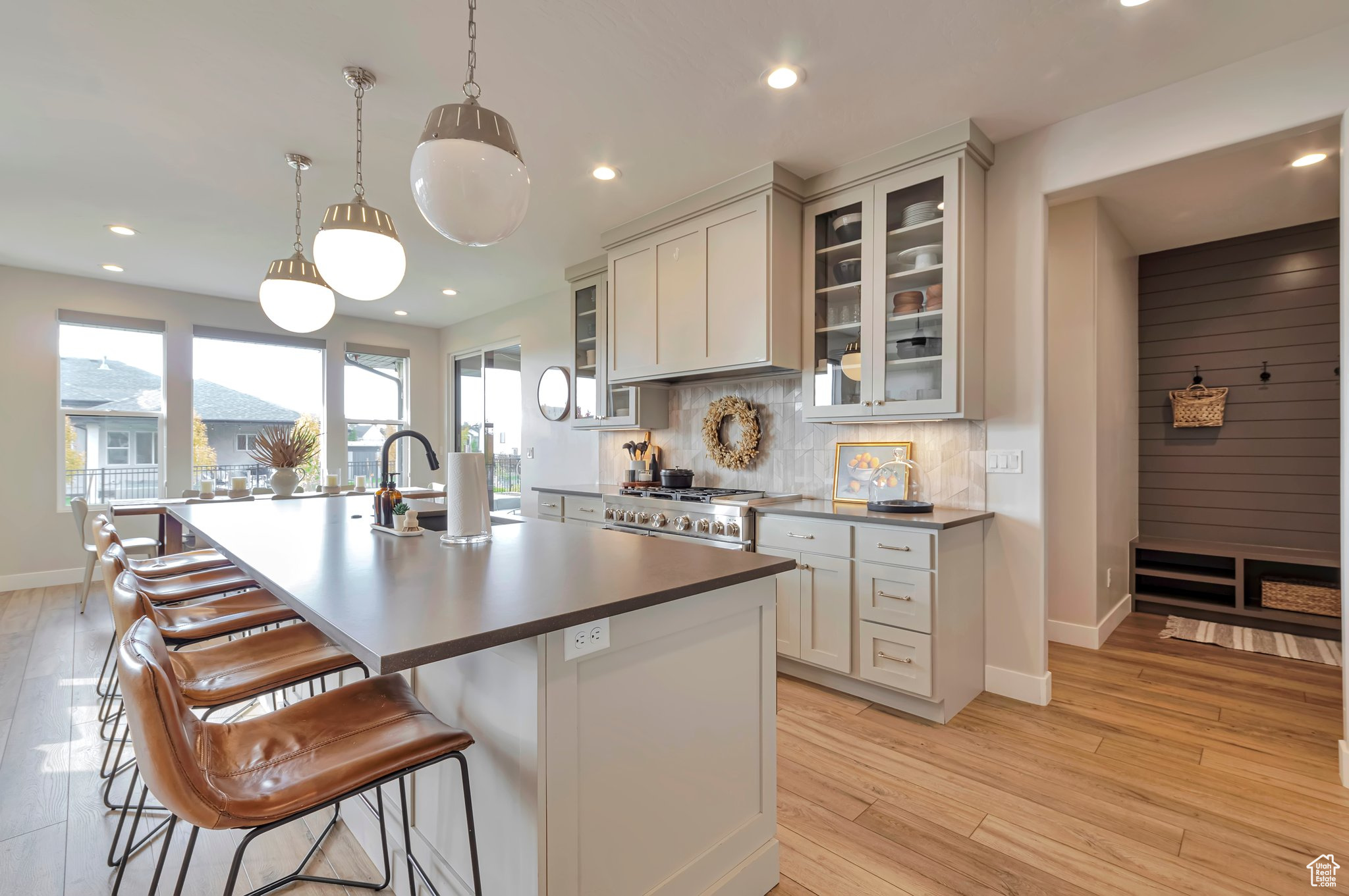 Kitchen with light hardwood / wood-style flooring, sink, backsplash, and an island with sink