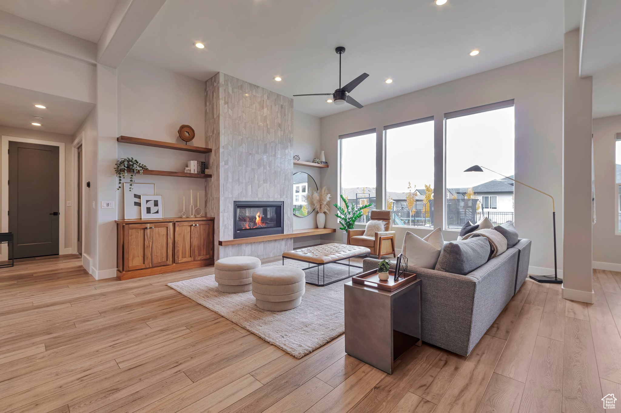 Living room featuring light hardwood / wood-style floors, a tiled fireplace, and ceiling fan