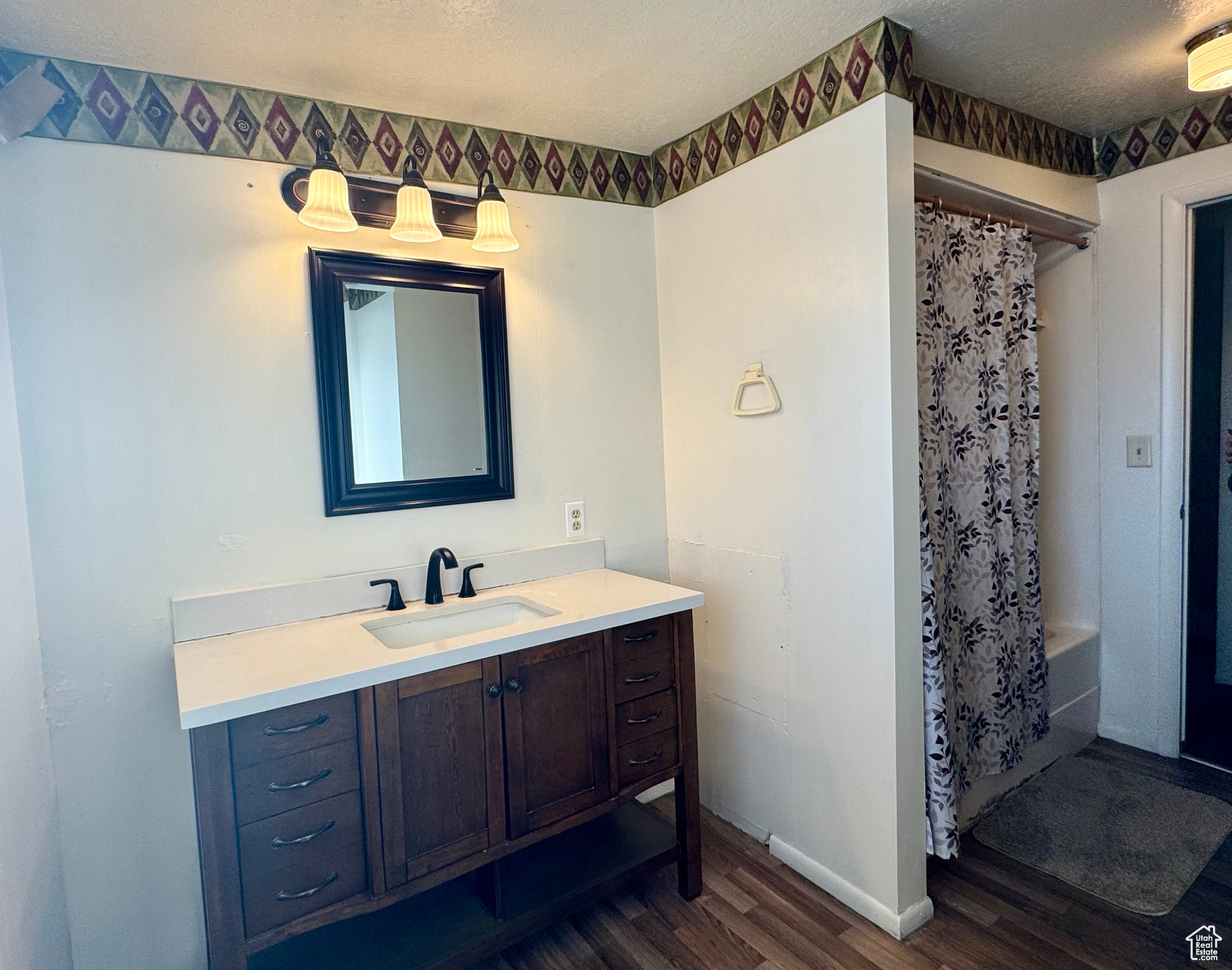 Bathroom with vanity, shower / bath combination with curtain, a textured ceiling, and hardwood / wood-style flooring