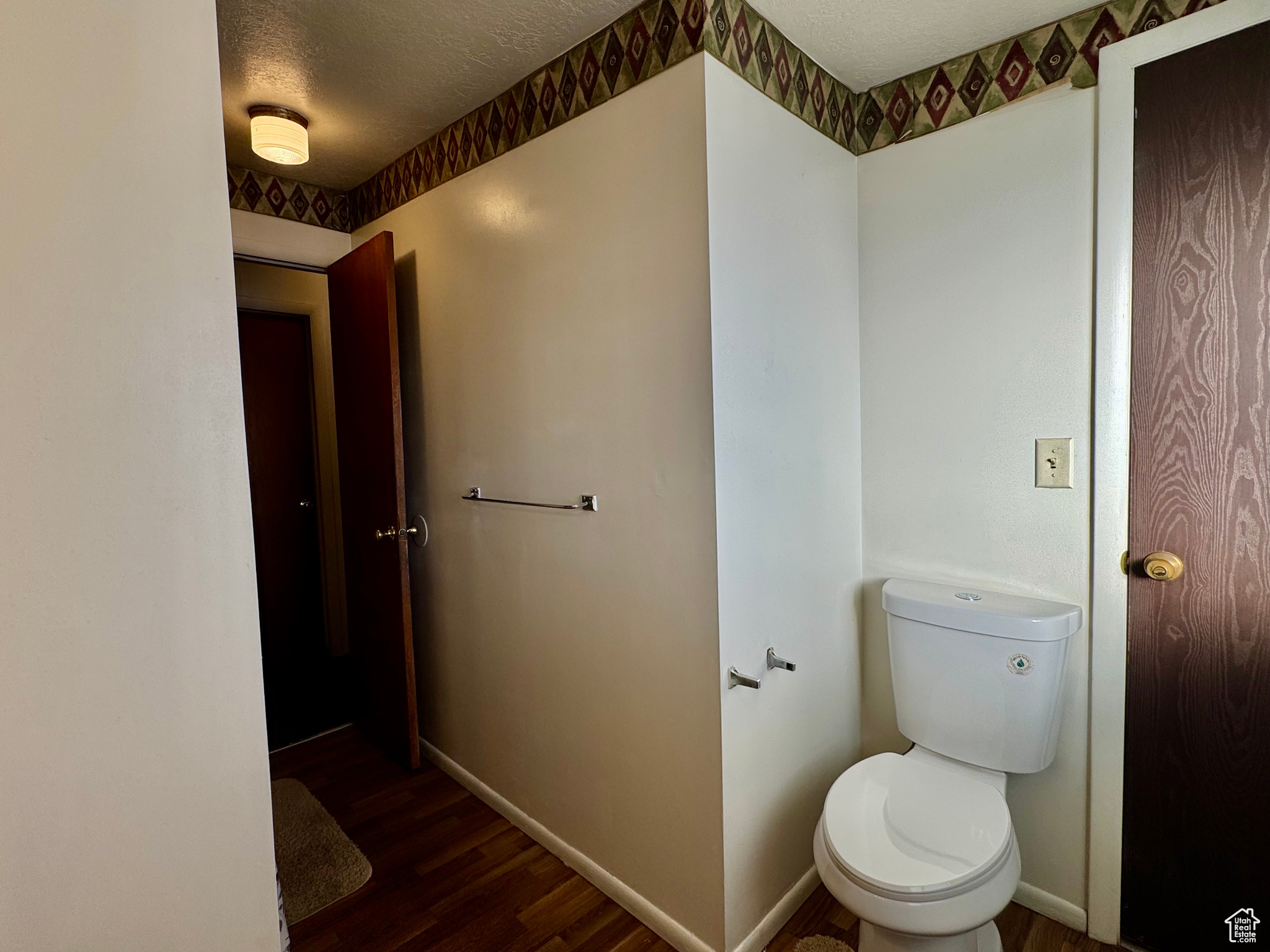 Bathroom featuring hardwood / wood-style flooring, toilet, and a textured ceiling