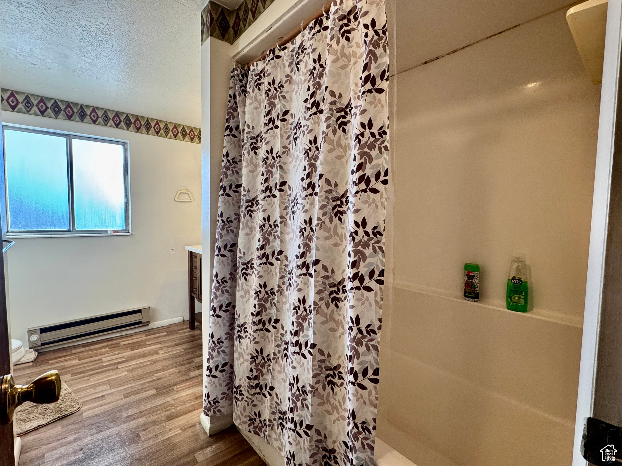 Bathroom featuring a shower with curtain, wood-type flooring, vanity, and a baseboard heating unit