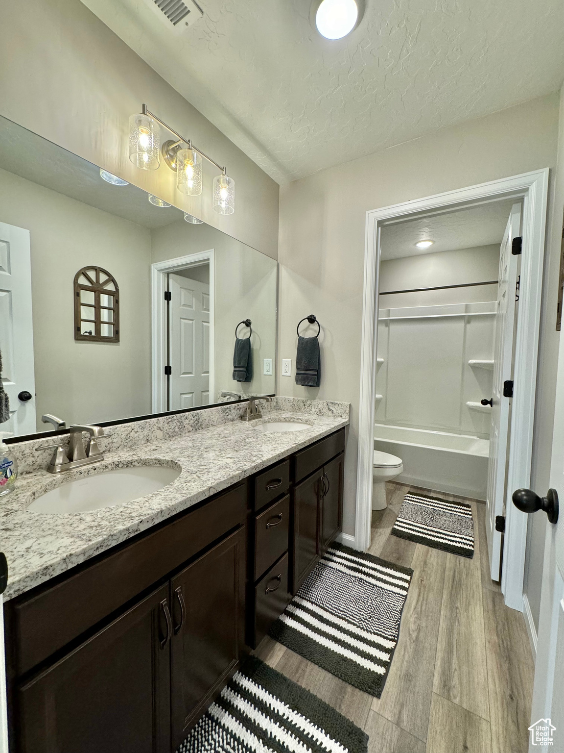 Upstairs Full bathroom with washtub / shower combination, a textured ceiling, hardwood / wood-style floors, toilet, and vanity