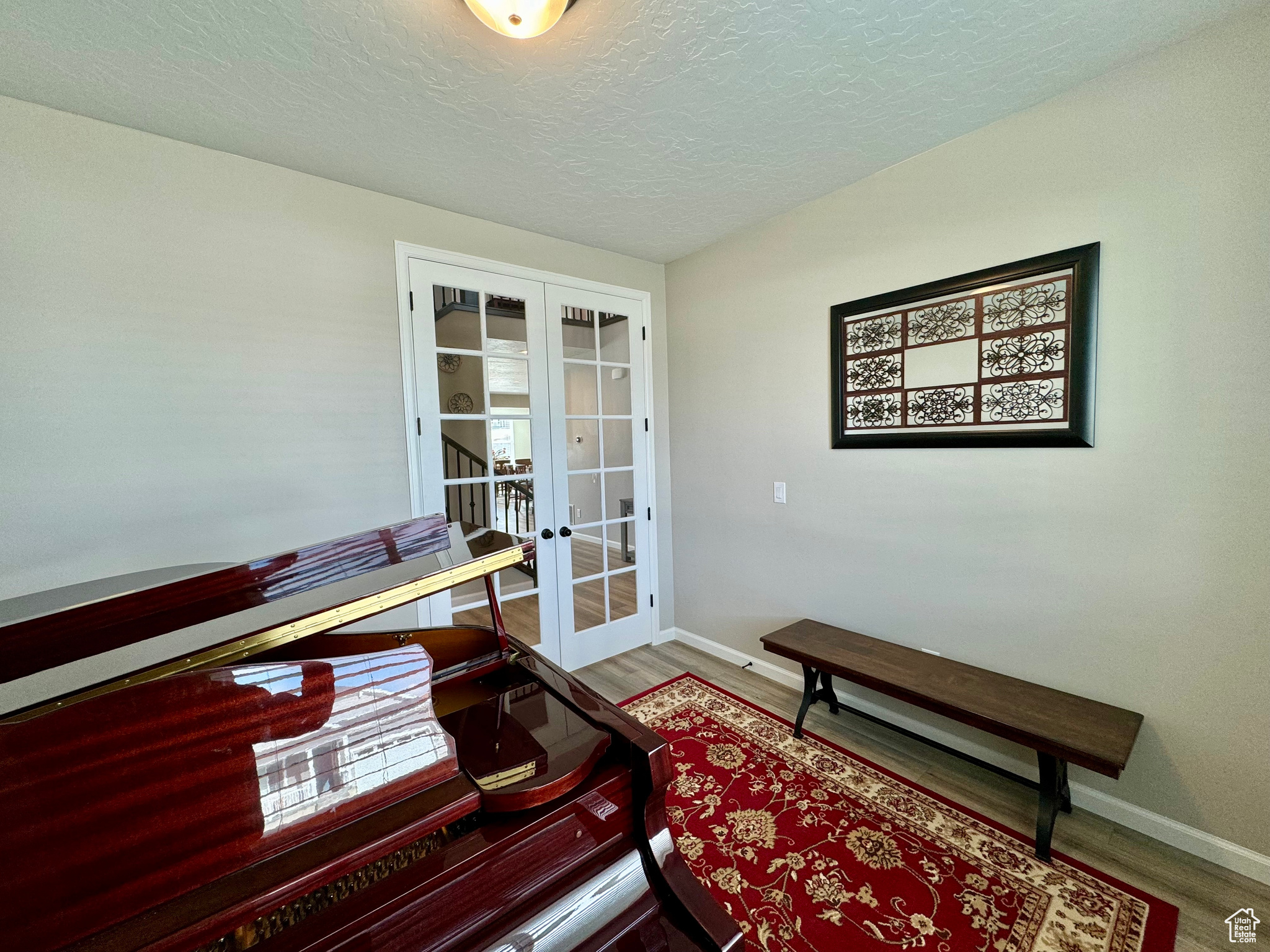 Piano Room, Office, or Bedroom, just left of the entry. Interior space with french doors, hardwood / wood-style flooring, and a textured ceiling