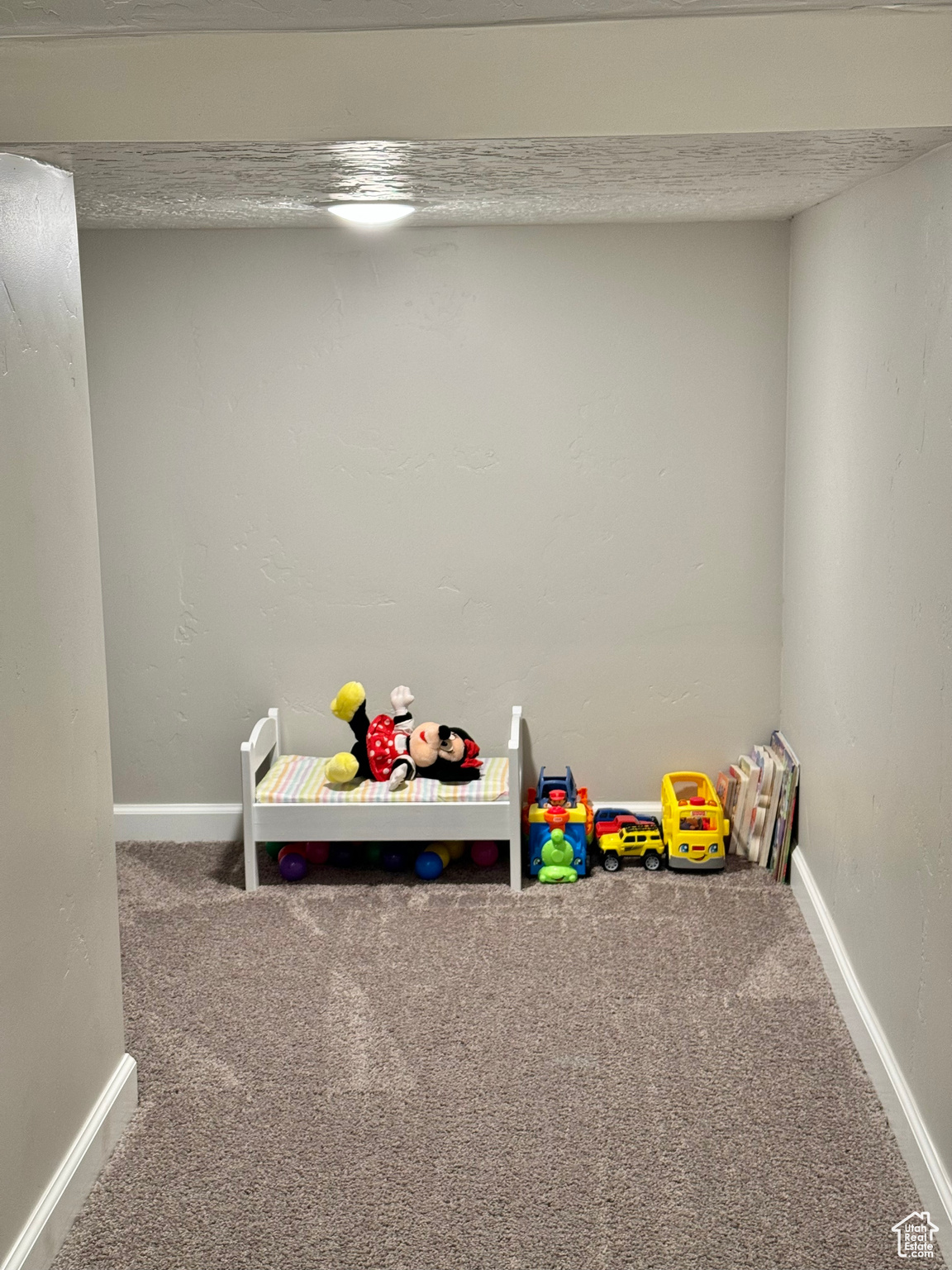 Basement Play Area under stairway  featuring carpet flooring and a textured ceiling