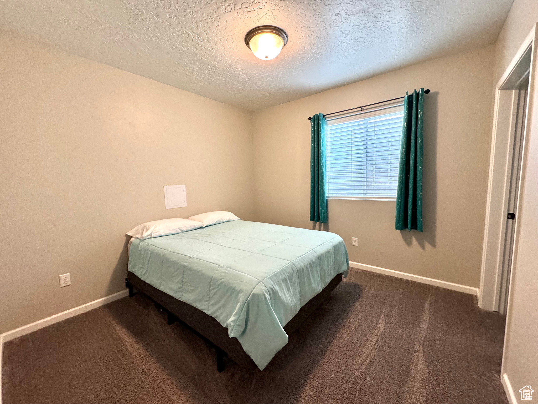 Basement Bedroom featuring a textured ceiling and dark colored carpet