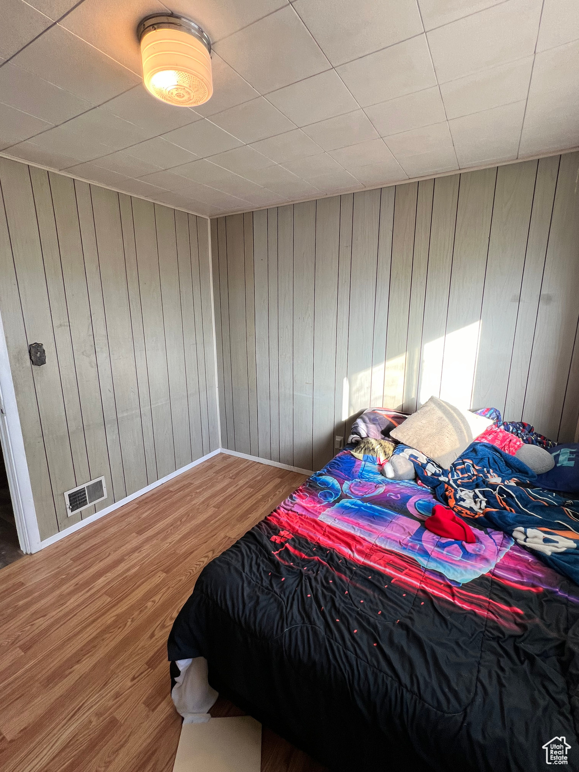 Bedroom with hardwood / wood-style floors and wooden walls