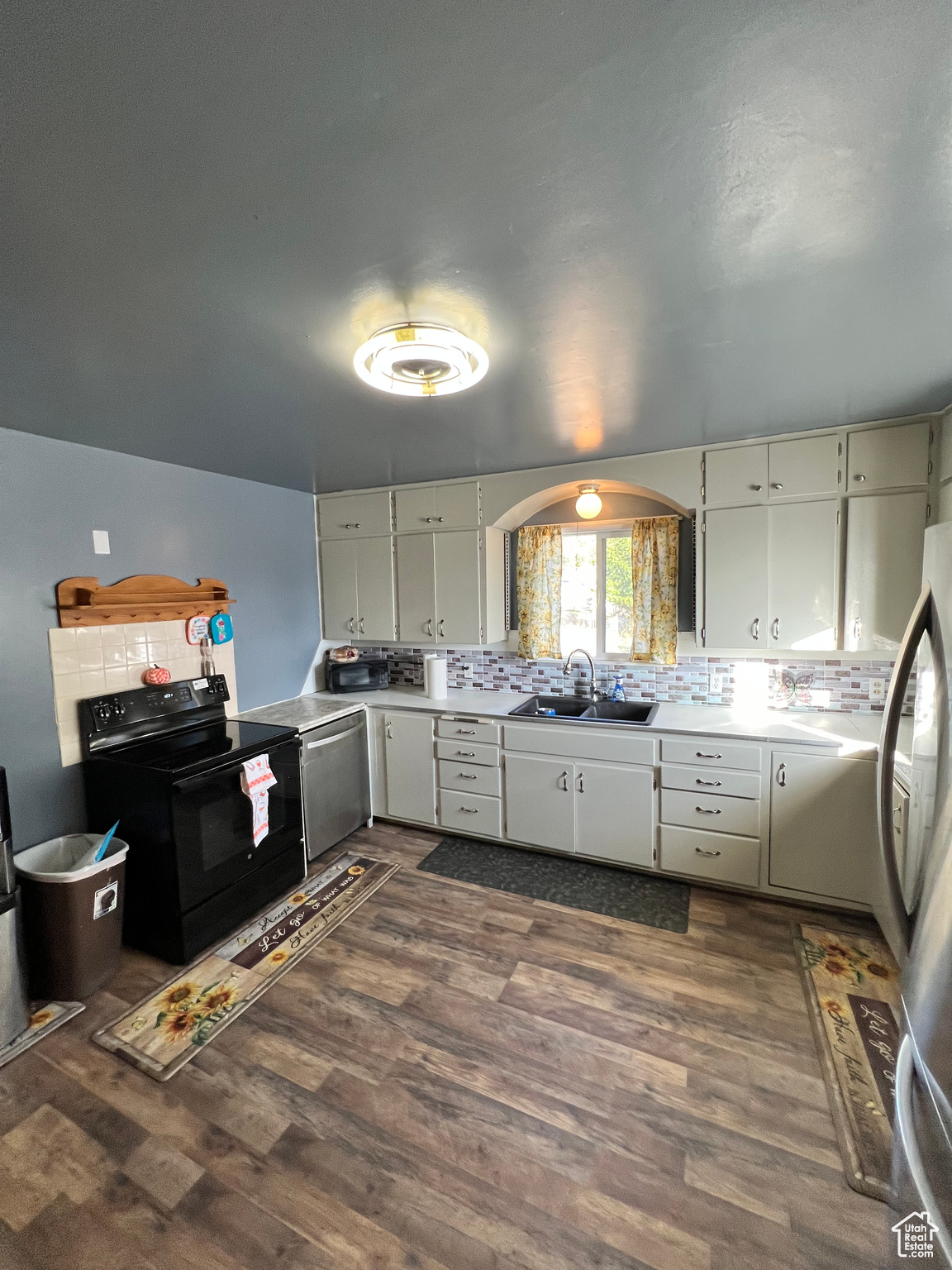 Kitchen with decorative backsplash, sink, electric range, white cabinetry, and dark hardwood / wood-style flooring