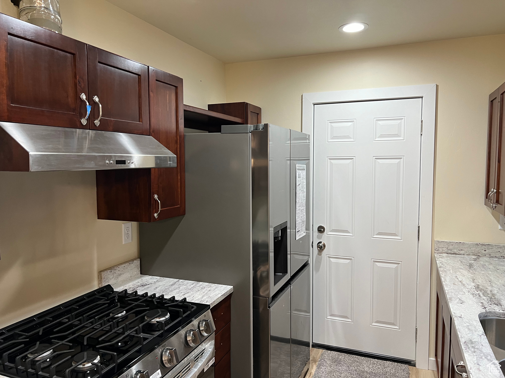 Kitchen featuring stainless steel stove and light stone counters