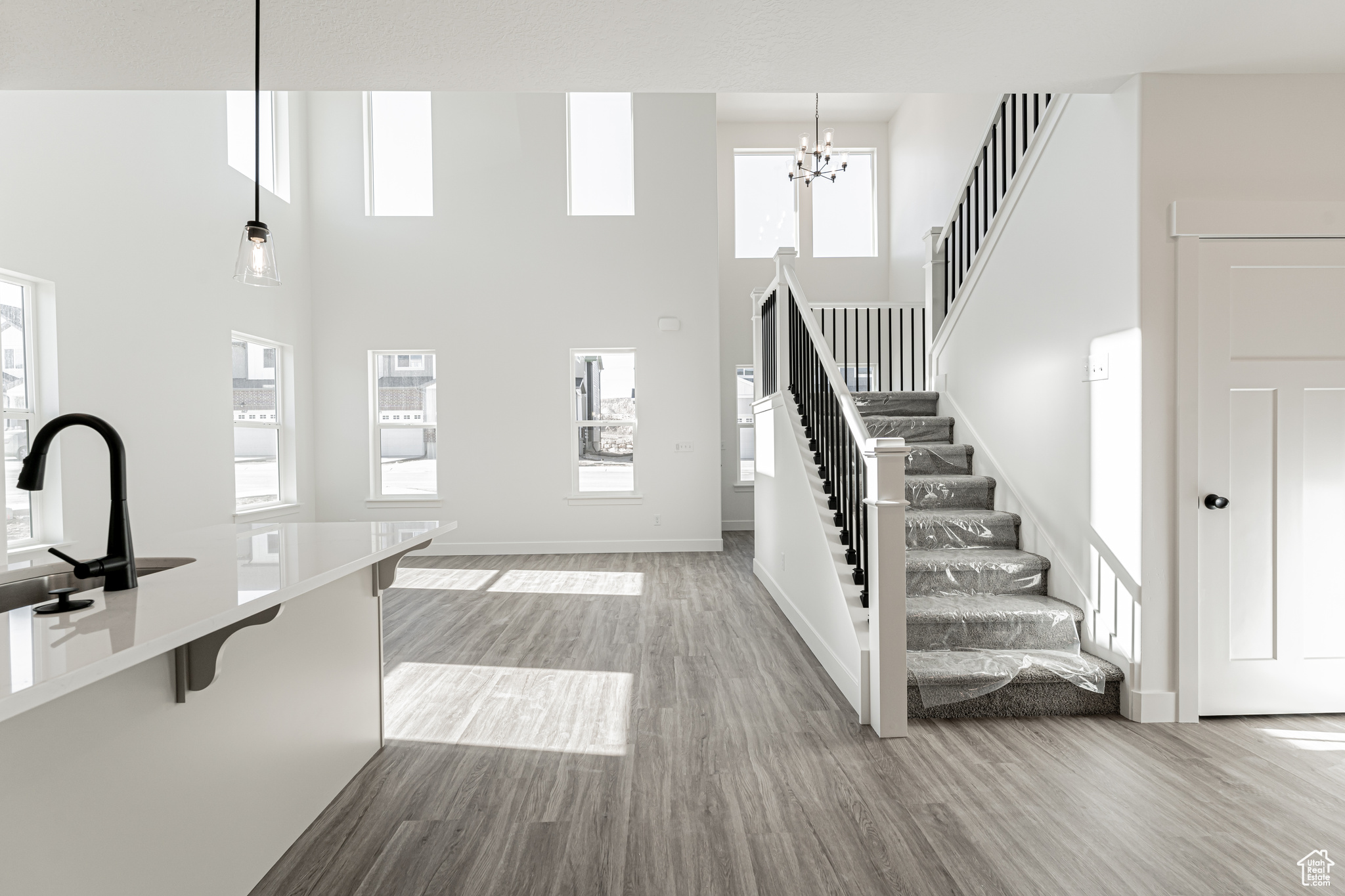 Interior space featuring a wealth of natural light, baseboards, a towering ceiling, and wood finished floors