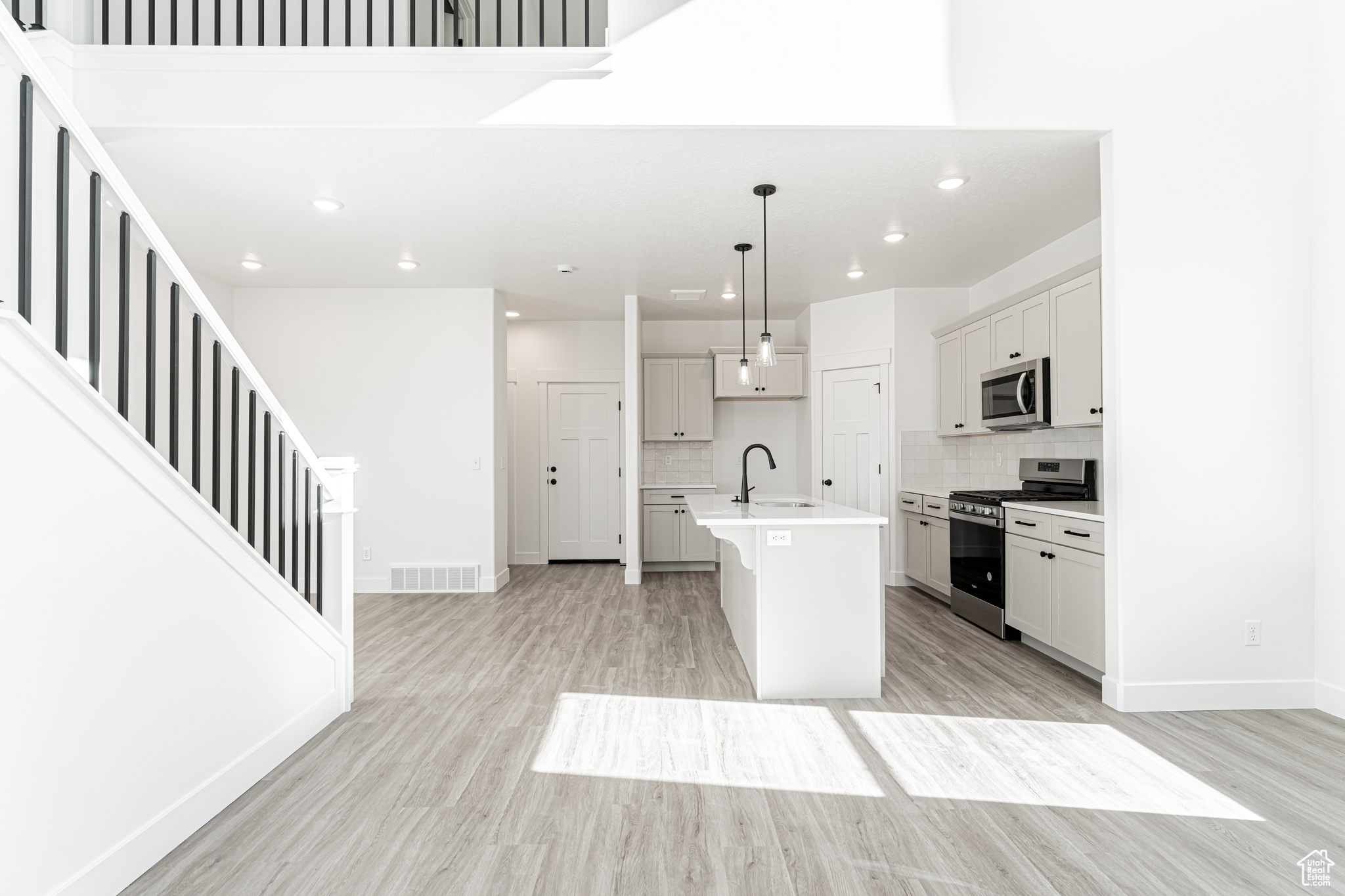 Kitchen featuring a center island with sink, visible vents, a sink, light countertops, and appliances with stainless steel finishes