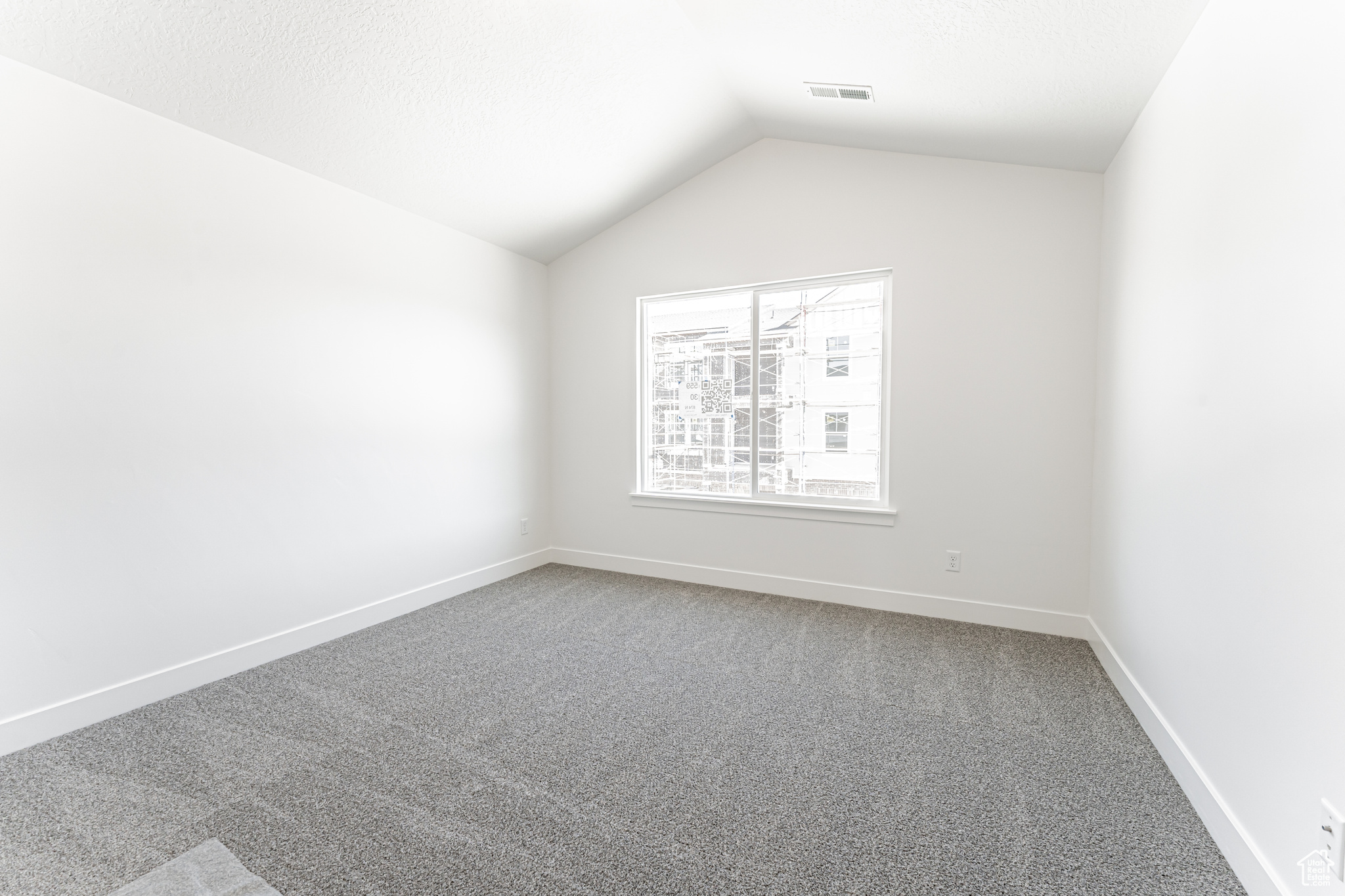 Carpeted spare room with lofted ceiling, baseboards, and visible vents