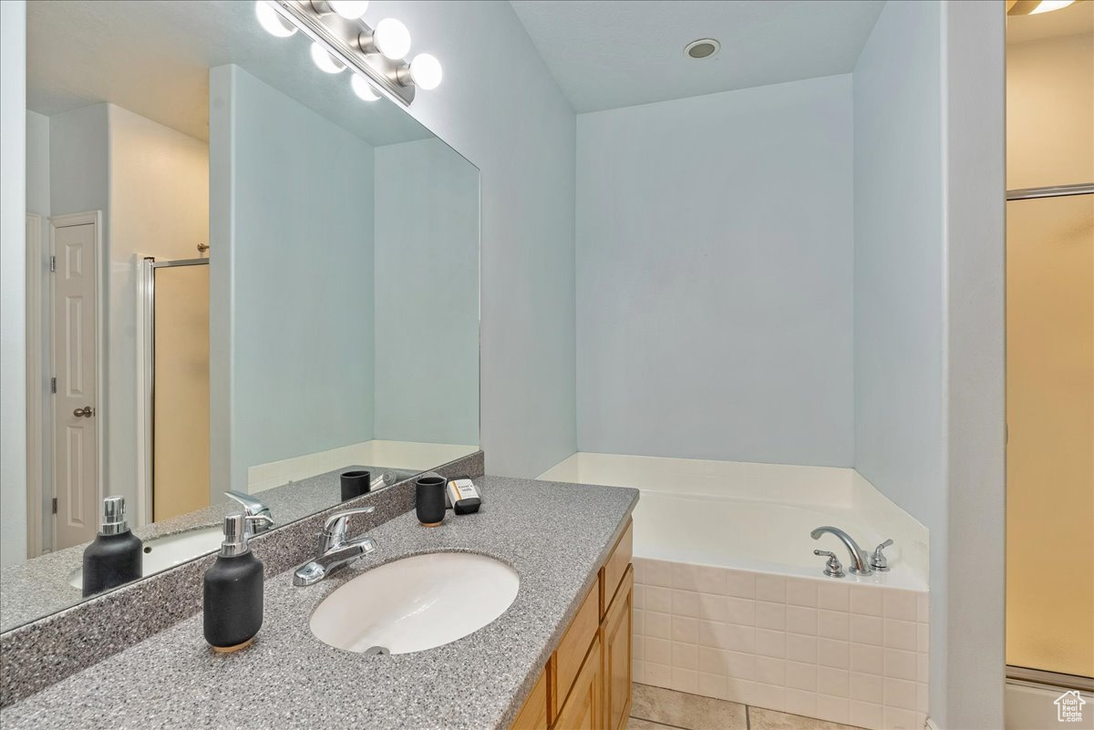 Bathroom featuring tile patterned flooring, shower with separate bathtub, and vanity