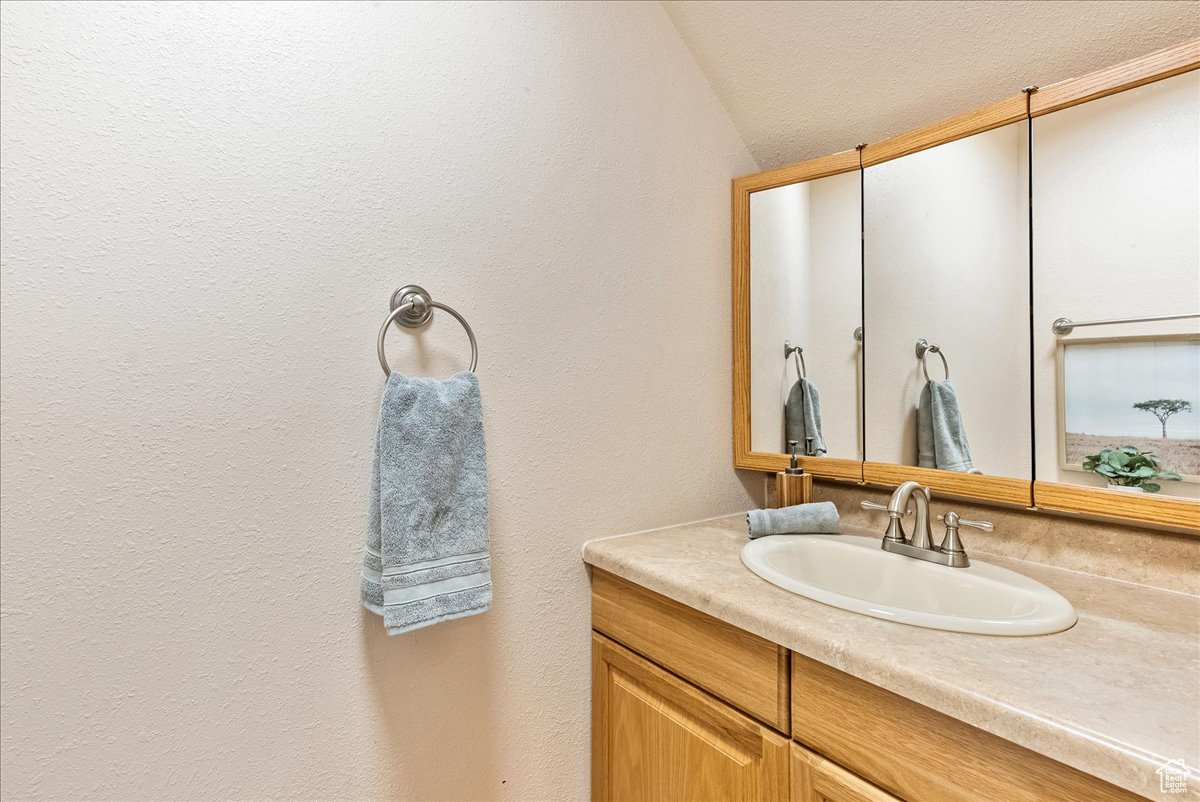 Bathroom with vanity and lofted ceiling