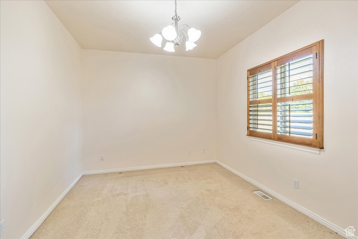 Spare room with light carpet and a chandelier