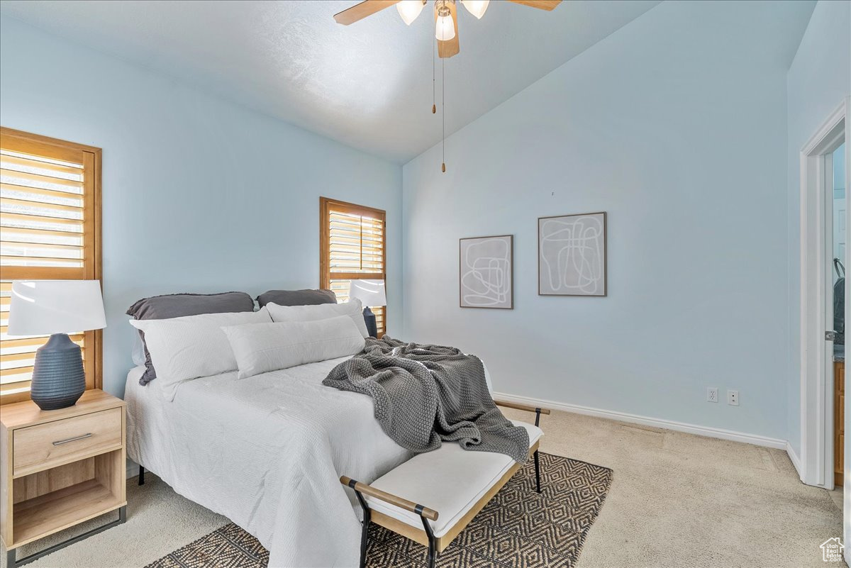 Carpeted bedroom with high vaulted ceiling and ceiling fan