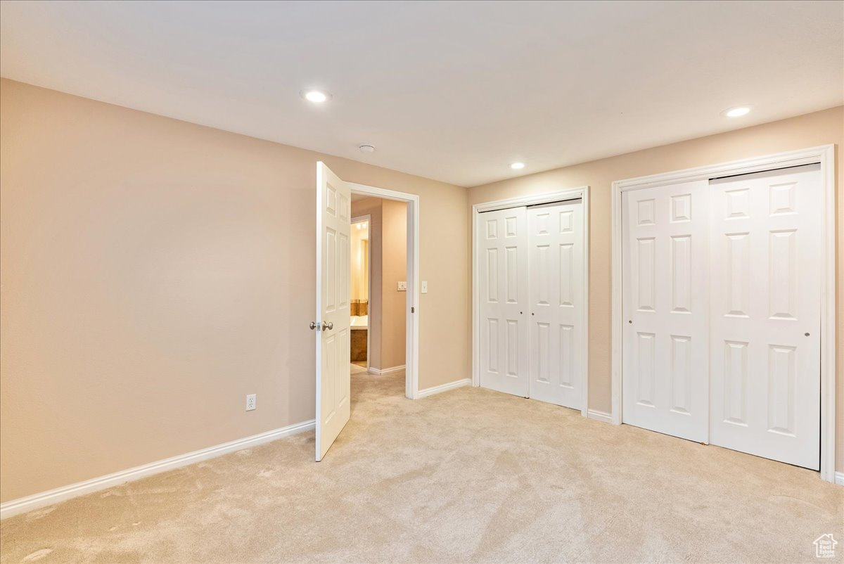 Unfurnished bedroom featuring light carpet and two closets