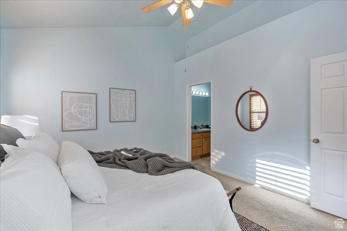 Bedroom with ensuite bath, light colored carpet, high vaulted ceiling, and ceiling fan