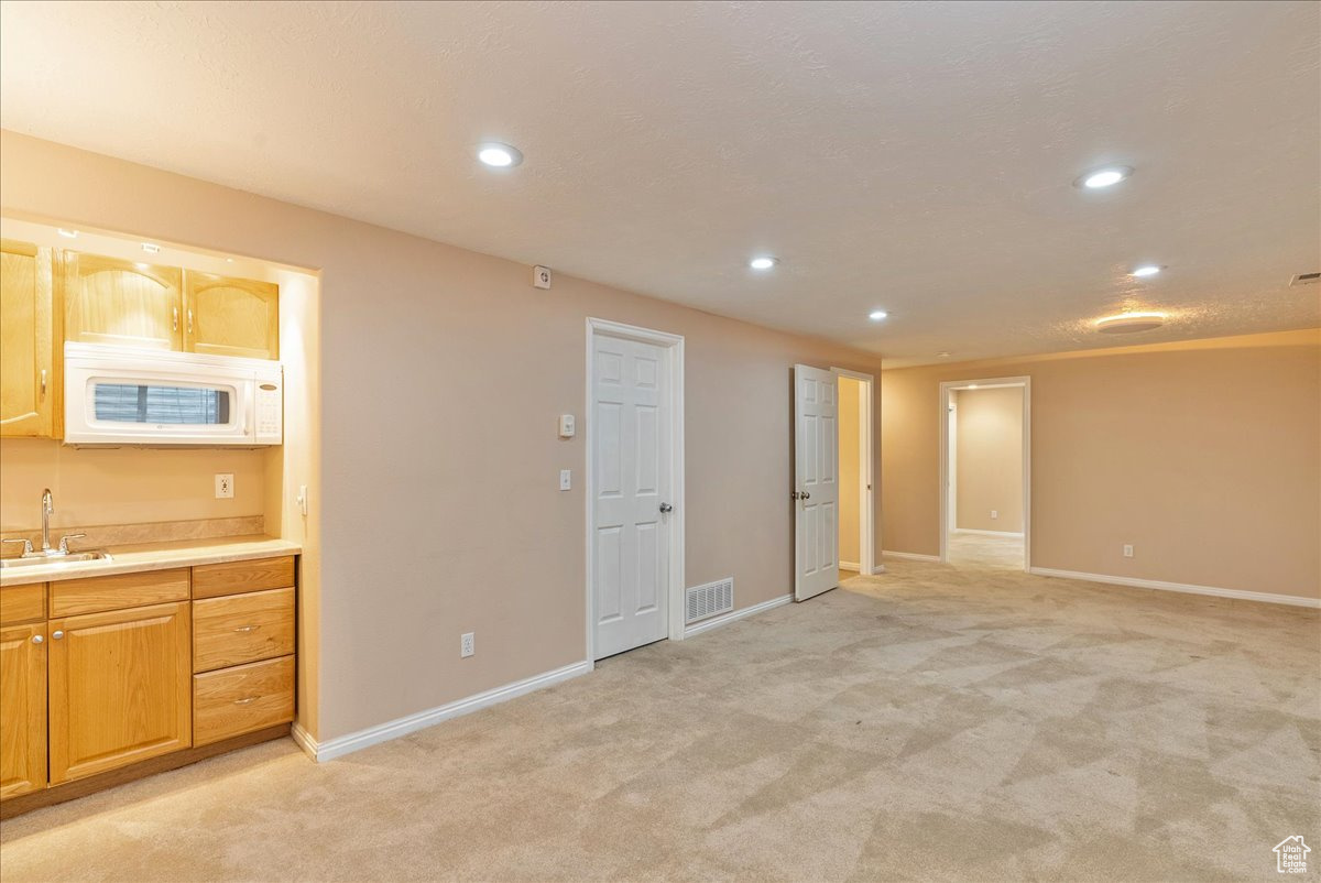 Interior space with light carpet and wet bar.