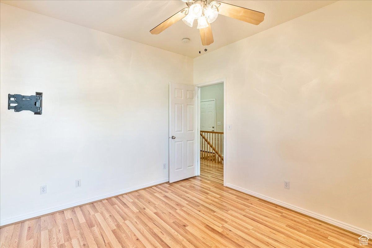 Empty room with ceiling fan and light hardwood / wood-style flooring