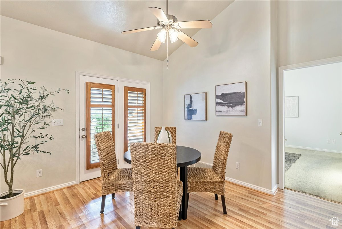 Dining area with light hardwood / wood-style floors, vaulted ceiling, and ceiling fan