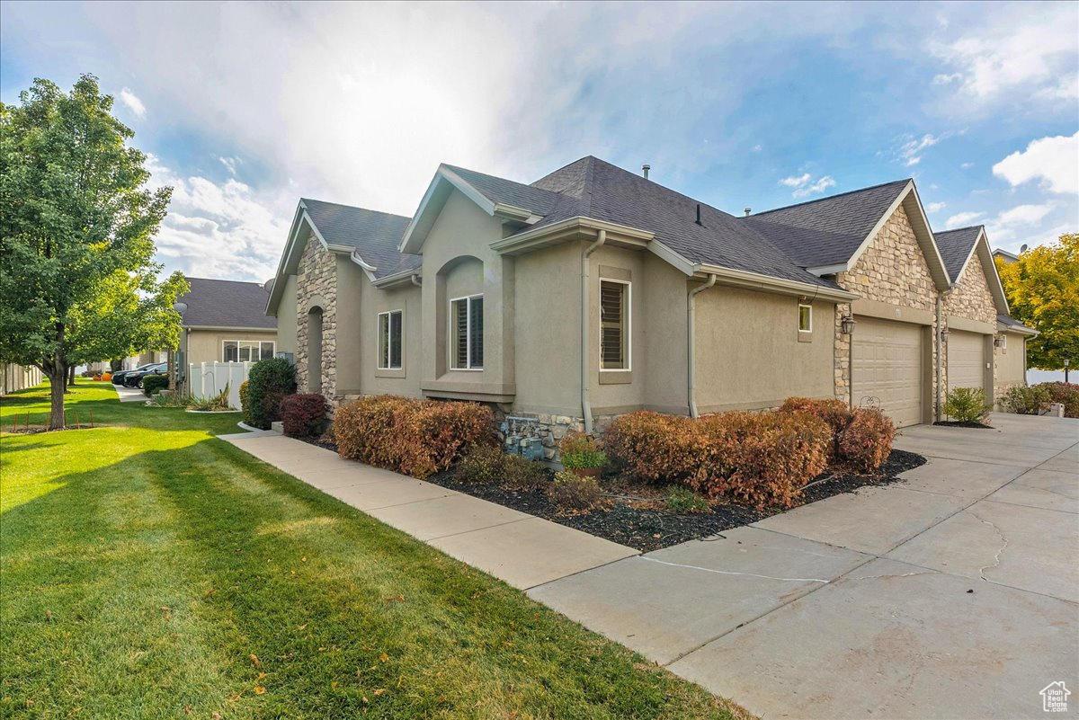 View of property exterior featuring a garage and a lawn