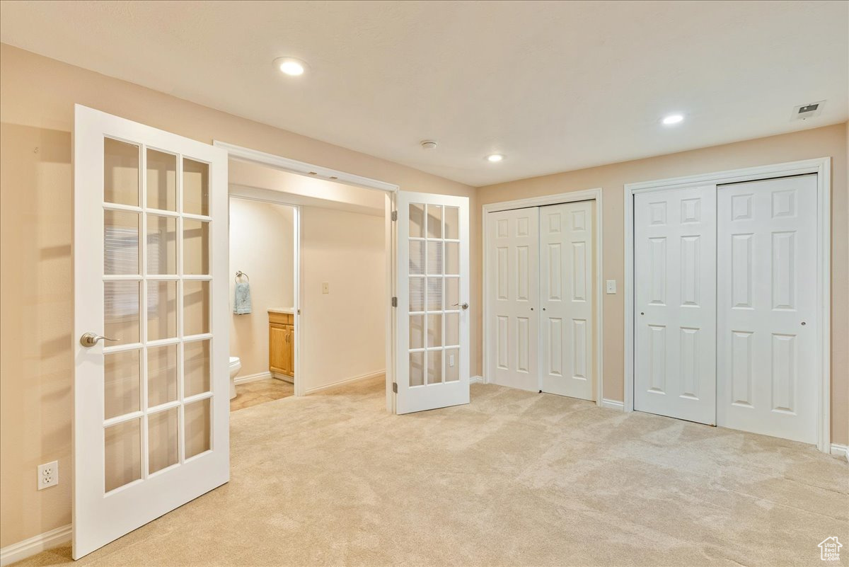 Interior space featuring french doors, two closets, and light colored carpet